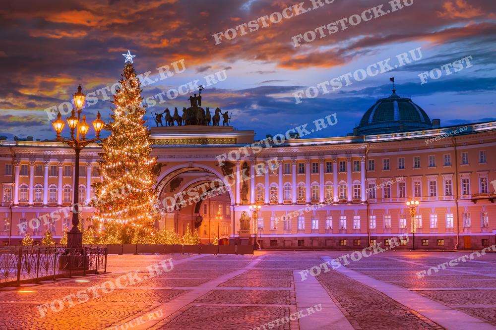На фотографии изображена новогодняя елка на Дворцовой площади в Санкт-Петербурге. Здание Главного штаба украшено яркими огнями и световыми инсталляциями. Вечернее освещение и зимняя атмосфера создают праздничное настроение. Закатное небо дополняет волшебство этого зимнего вечера.